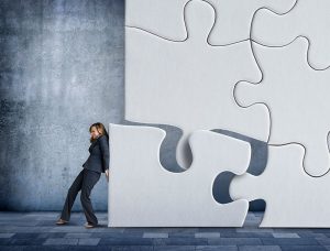 Business WOman Pushing Puzzle Piece Into Place